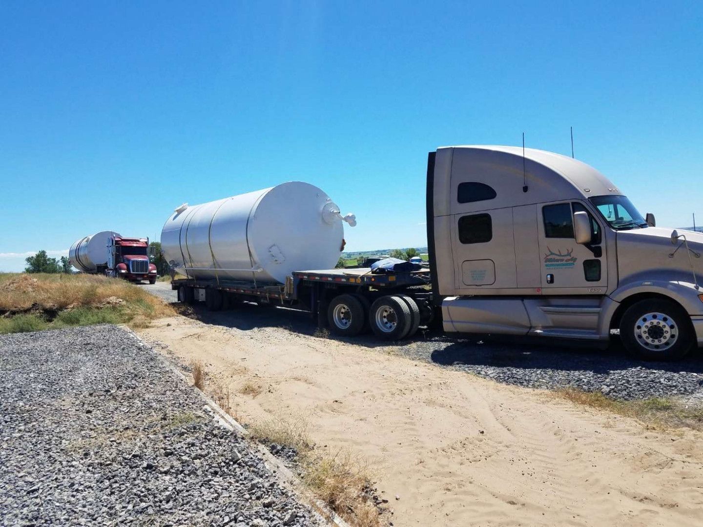 A semi truck is parked on the side of a dirt road.