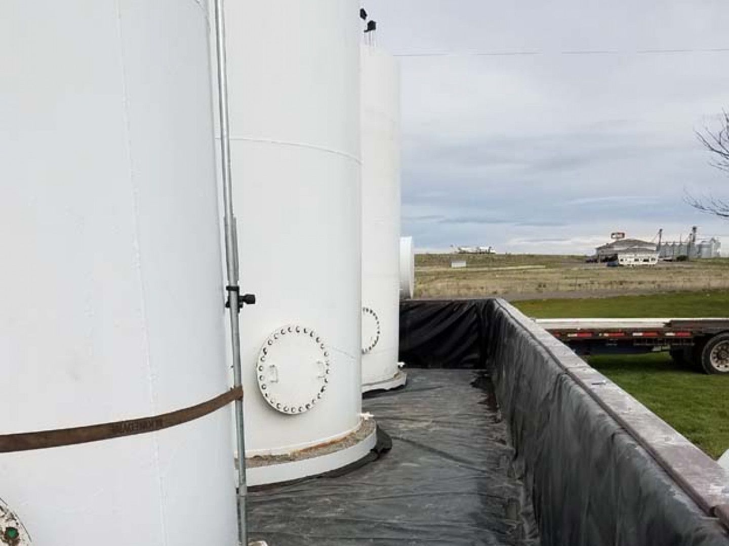A row of white tanks are sitting on top of a black tarp.