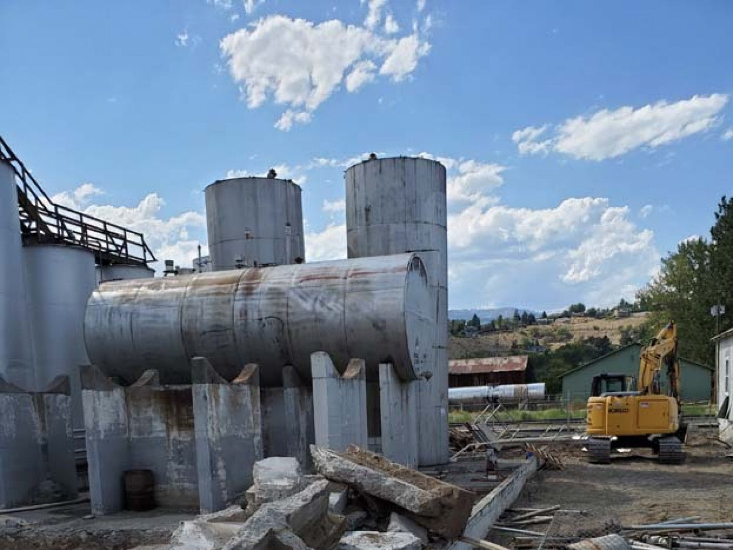 A yellow excavator is sitting in front of a building that is being demolished.