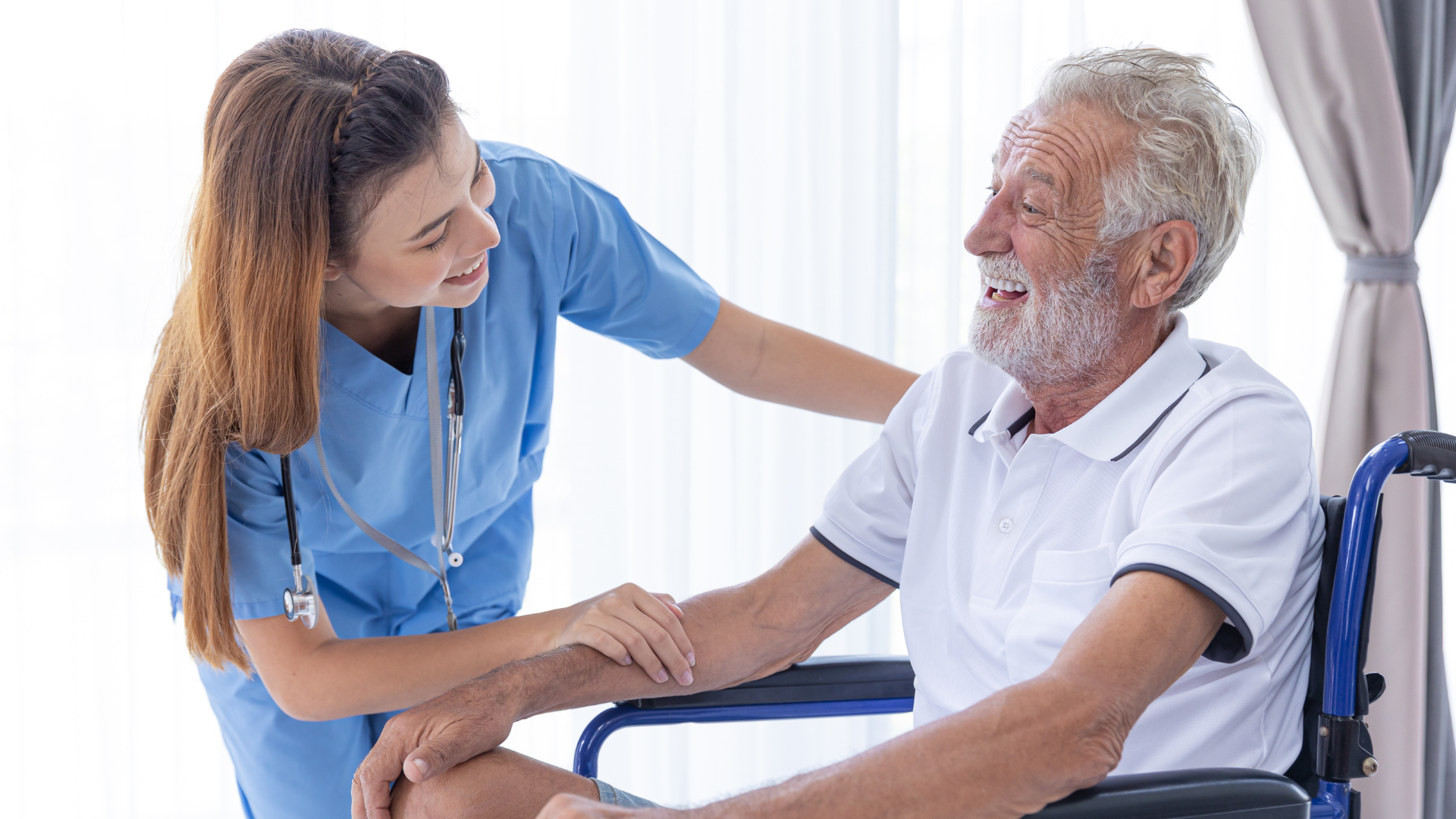 Nurse smiling and talking with a seated patient in a bright clinic room
