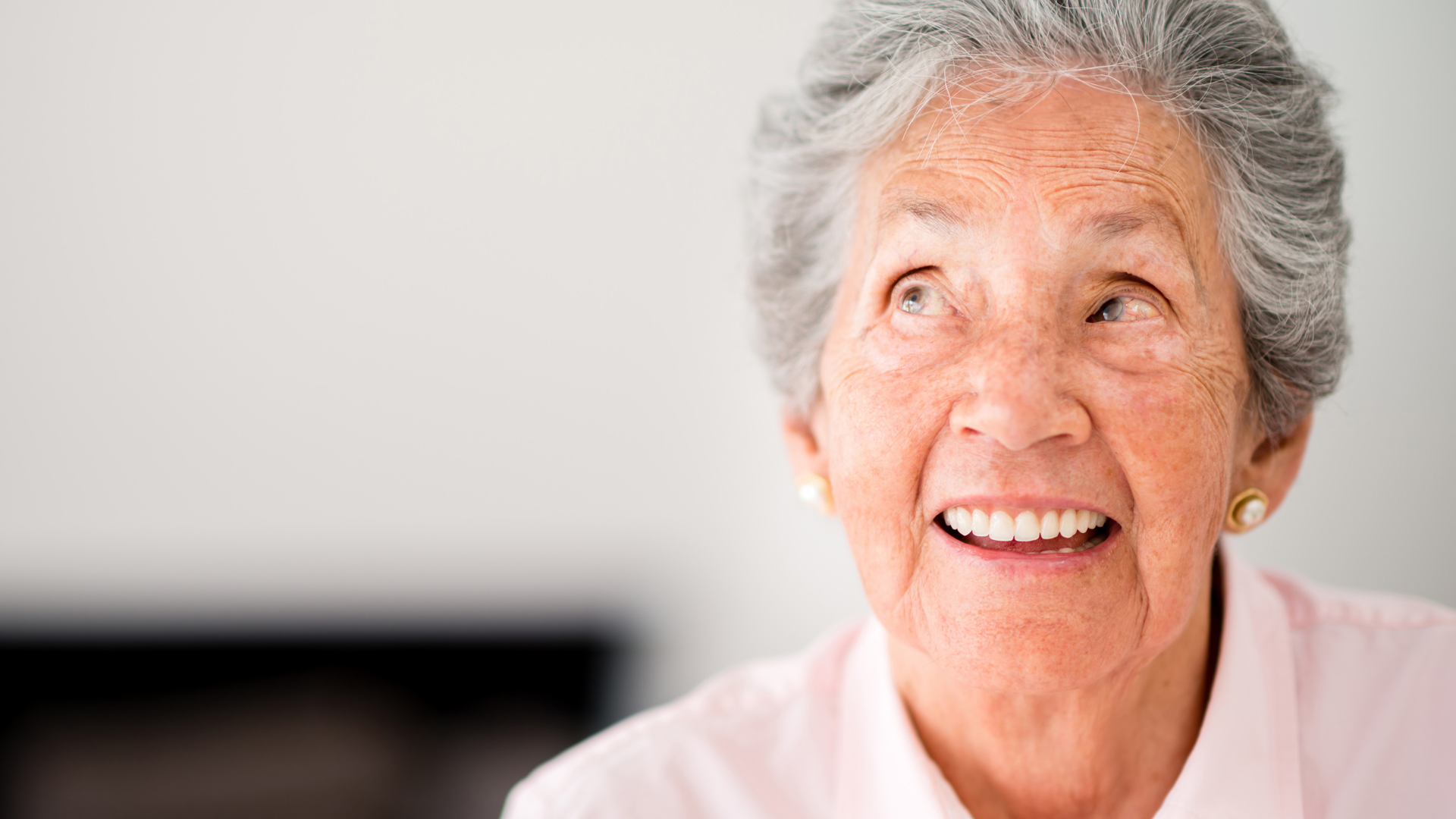 Smiling person in a light pink shirt against a soft gray background