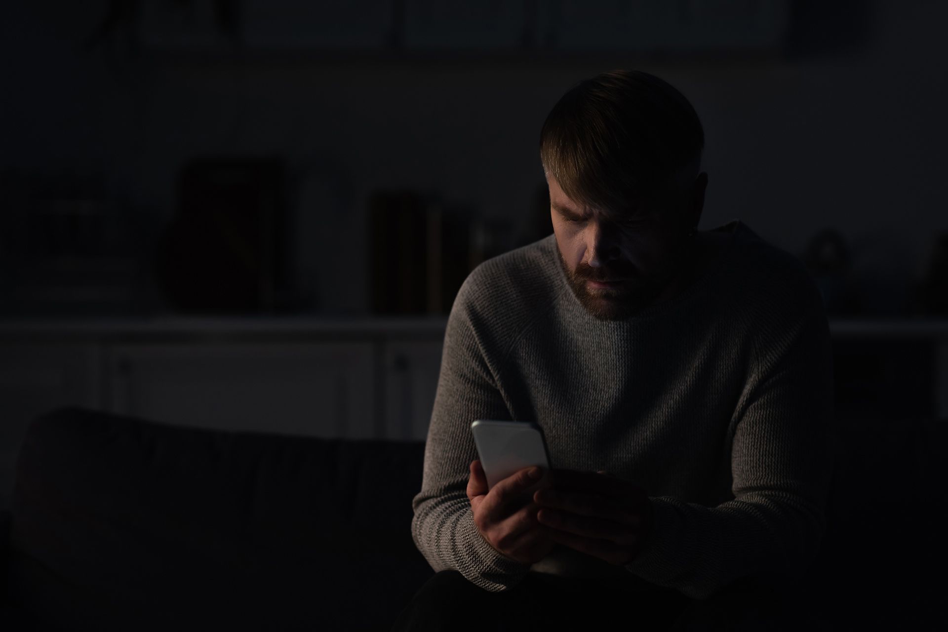 Person using a phone in a dark room during a power outage after an electrical failure. Person using a phone in a dark room during a power outage after an electrical failure.