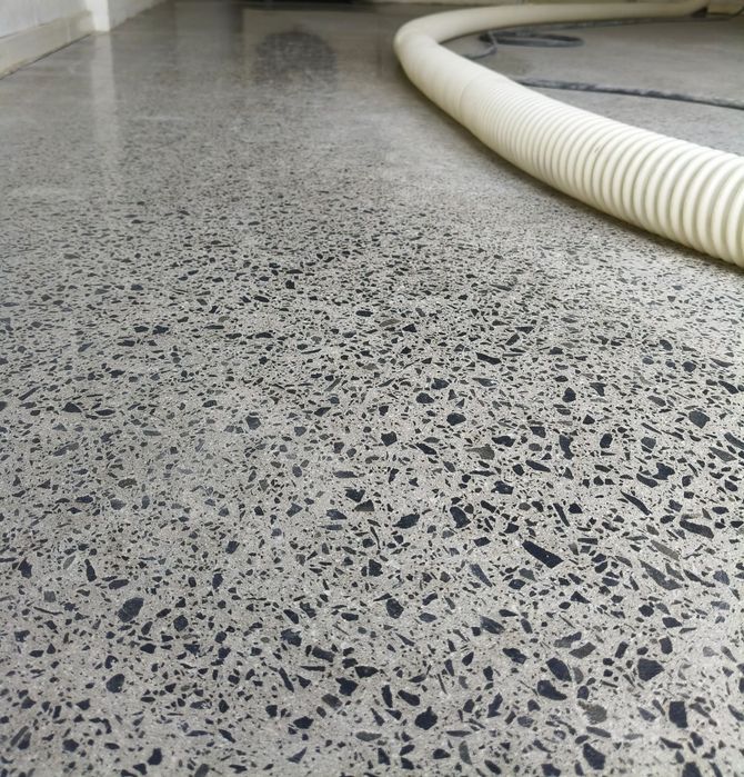 Polished concrete floor featuring Fully exposed aggregate. with a white industrial hose laying on the surface.