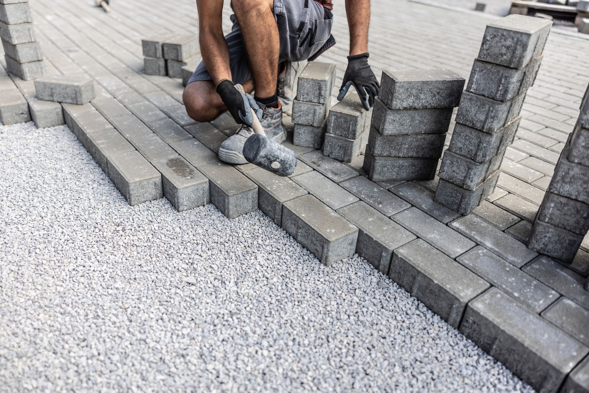 A man is paving a patio with concrete paving tiles.
