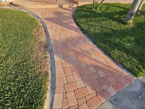 Brick walkway leading to steps, bordered by green grass.