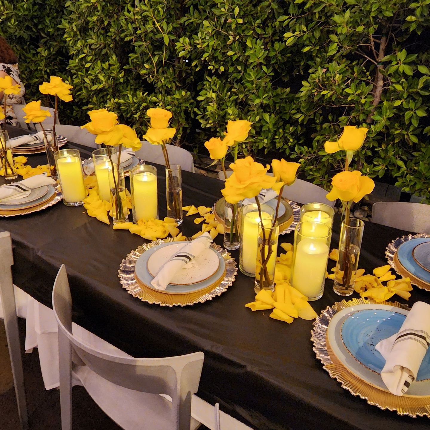 an elegant table setting for a large evening party, with lit candles and yellow roses