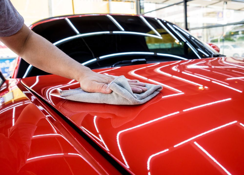 A Person Is Cleaning a Red Car with A Towel — Jetty Car Detailing Coffs Harbour in Coffs Harbour NSW