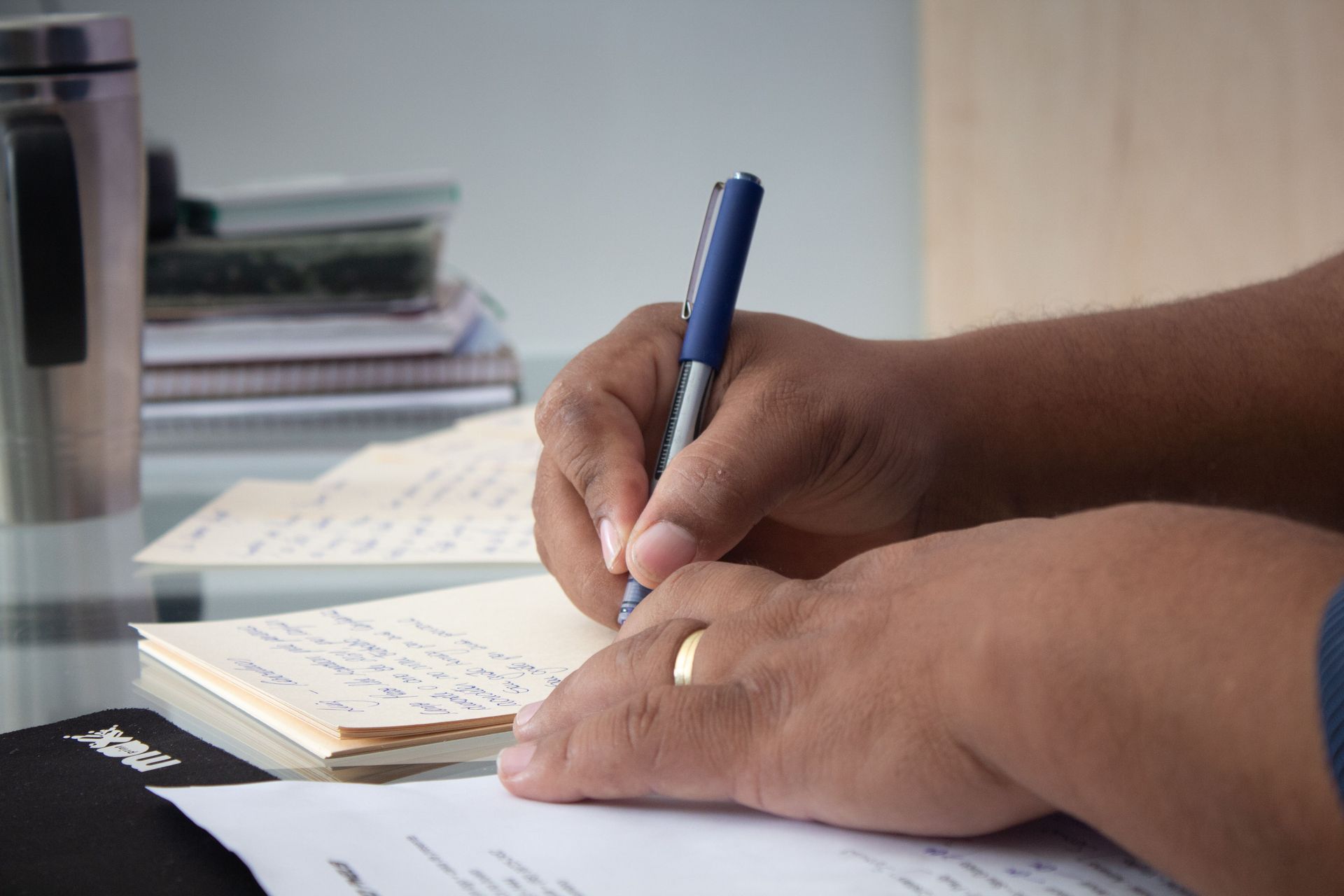 Hands filling out a document on a desk beside a laptop and pen