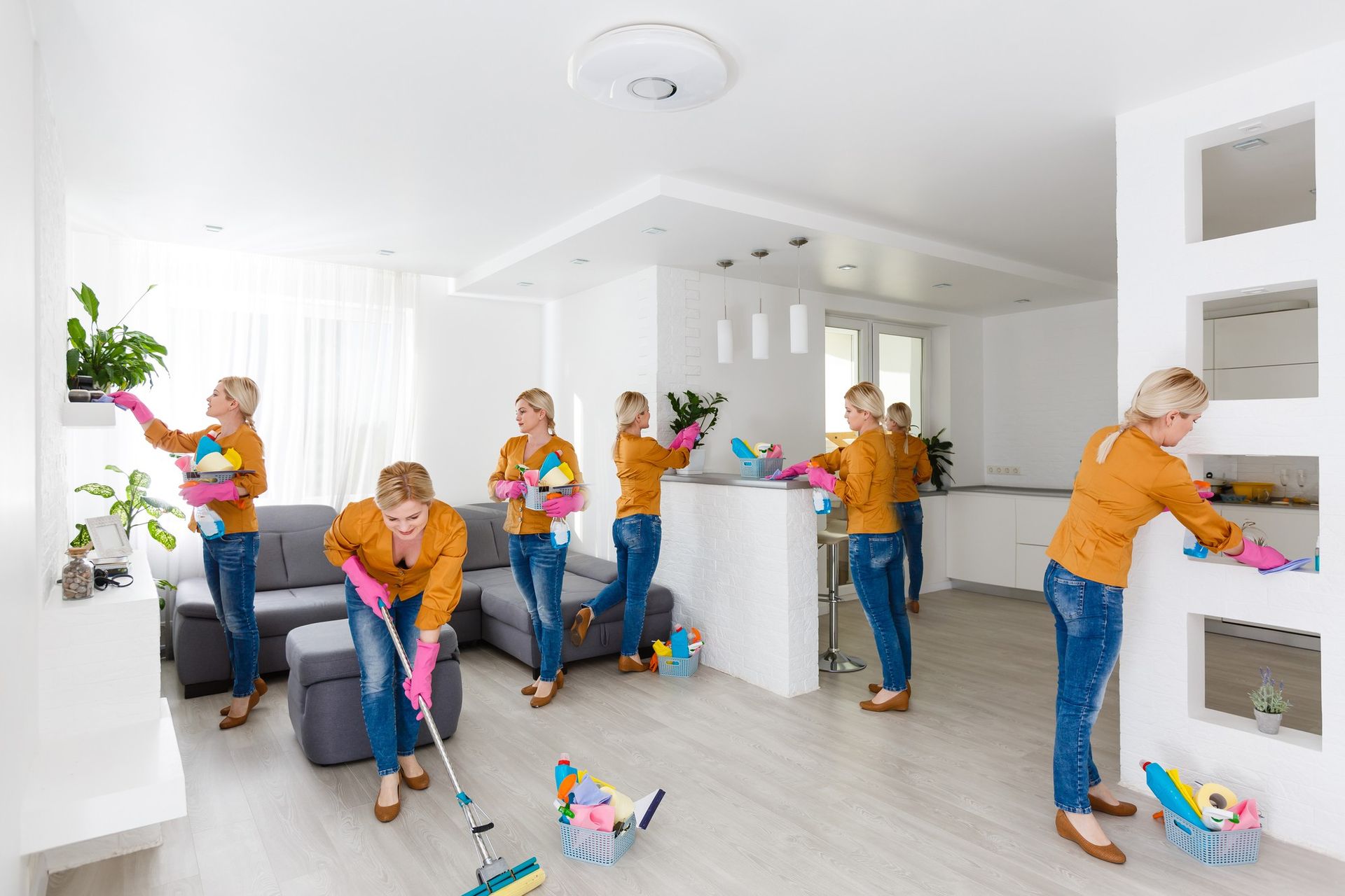People cleaning a bright white home, sweeping, dusting, and organizing toys in a living room and kitchen area.