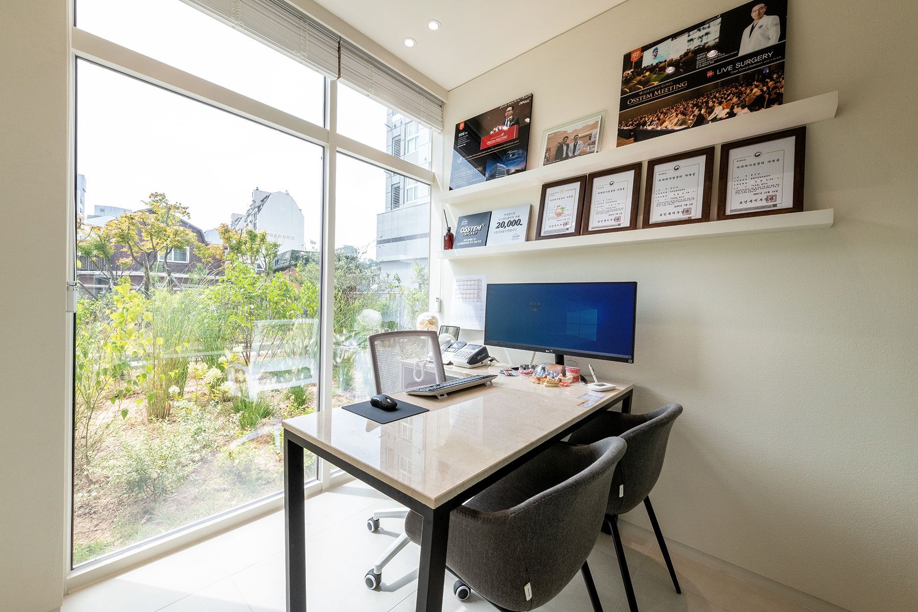 Bright home office with desk, computer, and window overlooking greenery.