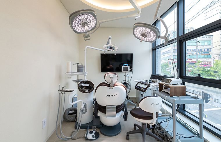 Dental operatory with chair, equipment, and large overhead lights.