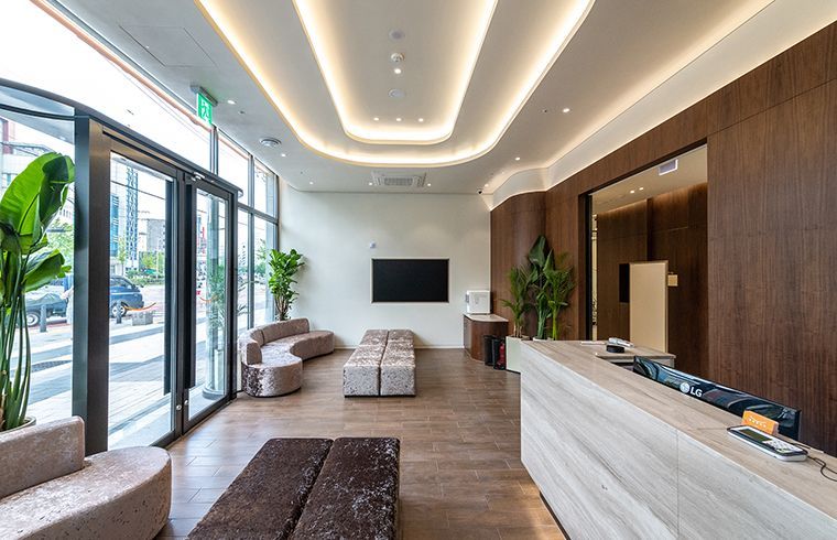 Modern clinic lobby with seating, plants, and a reception desk; wood and neutral tones.