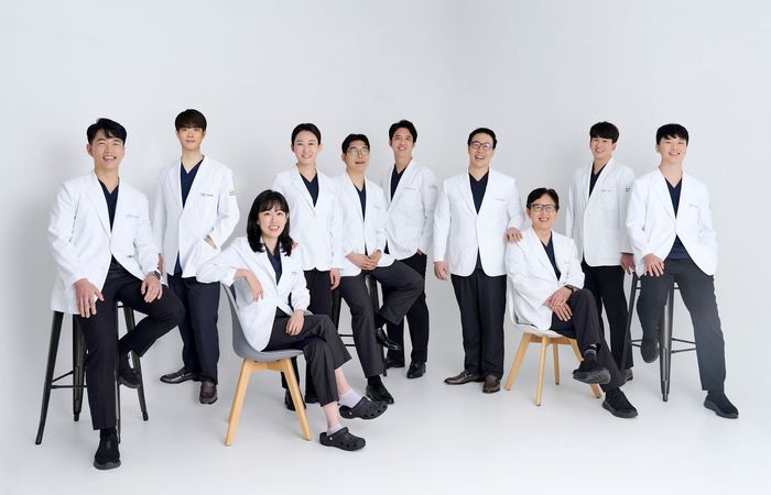 Staff of Heal Dental Clinic in white lab coats, smiling, posed against a white background.