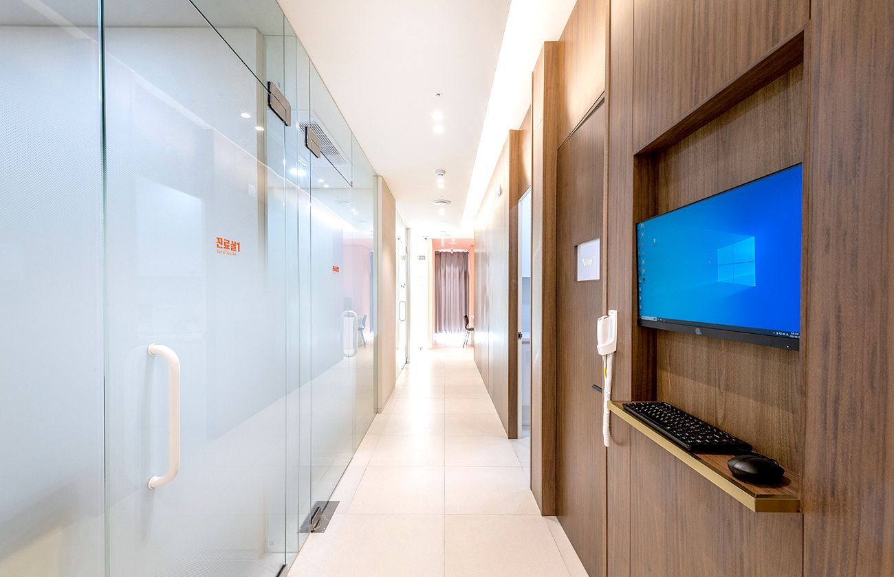 Hallway with glass doors, wood paneling, a computer, and a bright white floor.