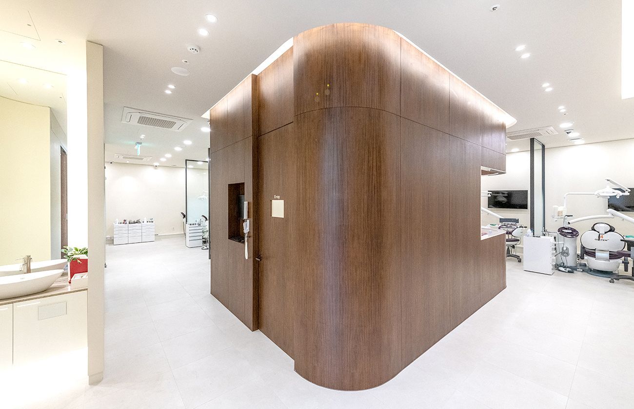 Modern dental office with a large wooden structure in the center, surrounded by dental equipment and white walls.