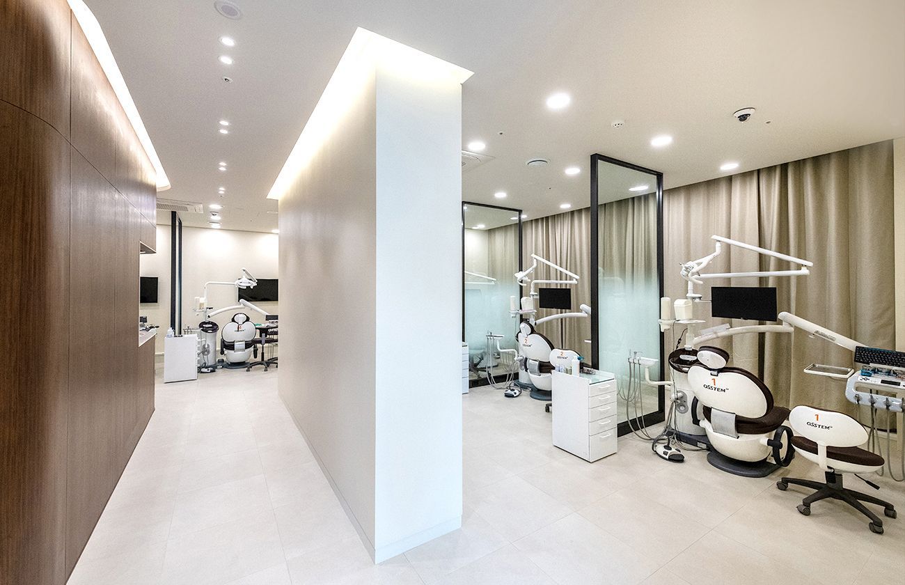 Modern dental clinic with treatment chairs behind glass partitions. Bright and clean interior.