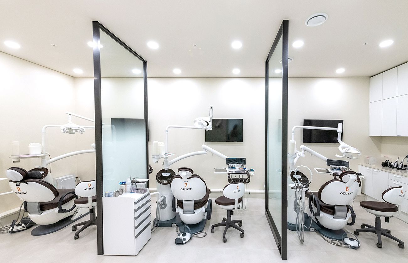 Modern dental office with three patient chairs separated by glass partitions.