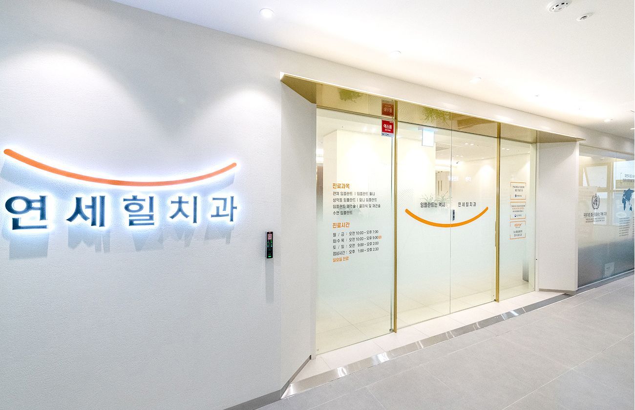 Entrance to a modern Korean dental clinic with glass doors and a sign in Korean.