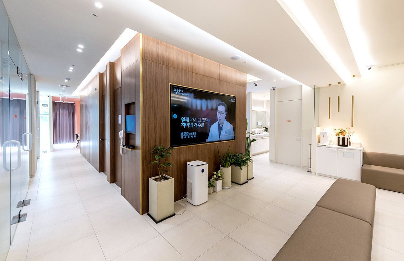 Modern waiting room with wood paneling, large TV screen, and seating.