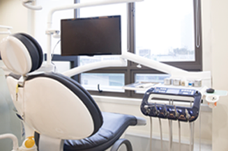 Dental chair in a modern office with a monitor and window in the background.