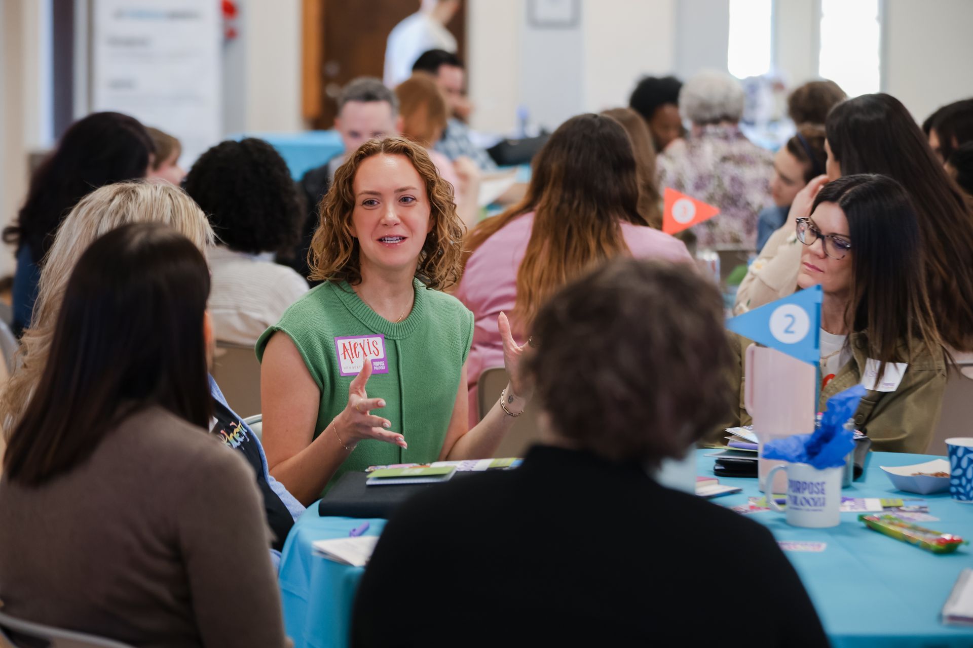 photo of woman speaking to a roundtable of other people listening