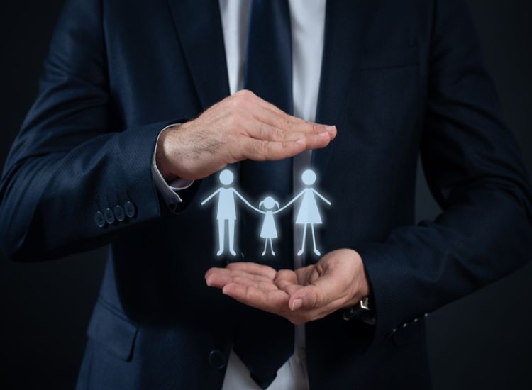 Businessperson cupping glowing family icons in hands against a dark background