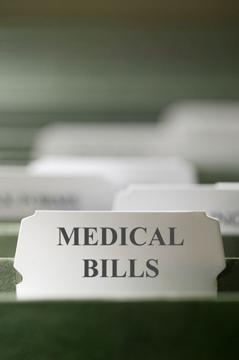 File tab labeled “MEDICAL BILLS” in a stack of papers on a desk