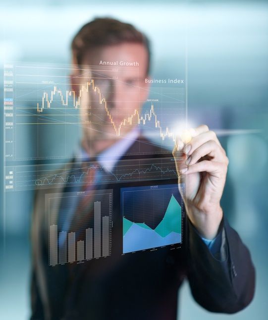 Businessperson in suit analyzing charts on a transparent screen in a blurred office setting