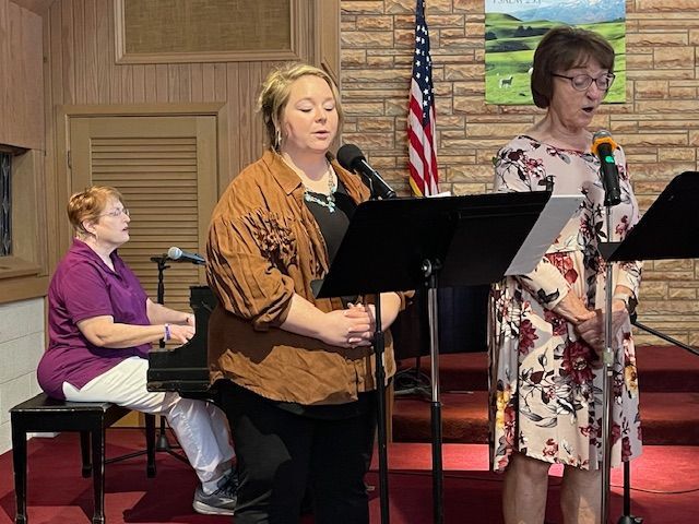 A group of women are singing in front of microphones in a church.