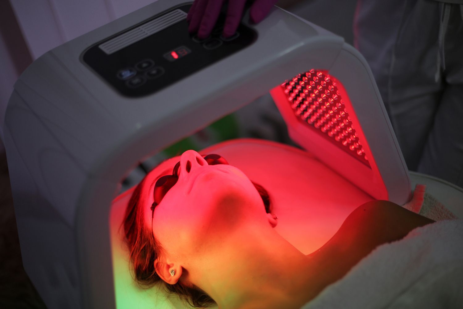 A woman is getting a led light treatment on her face.