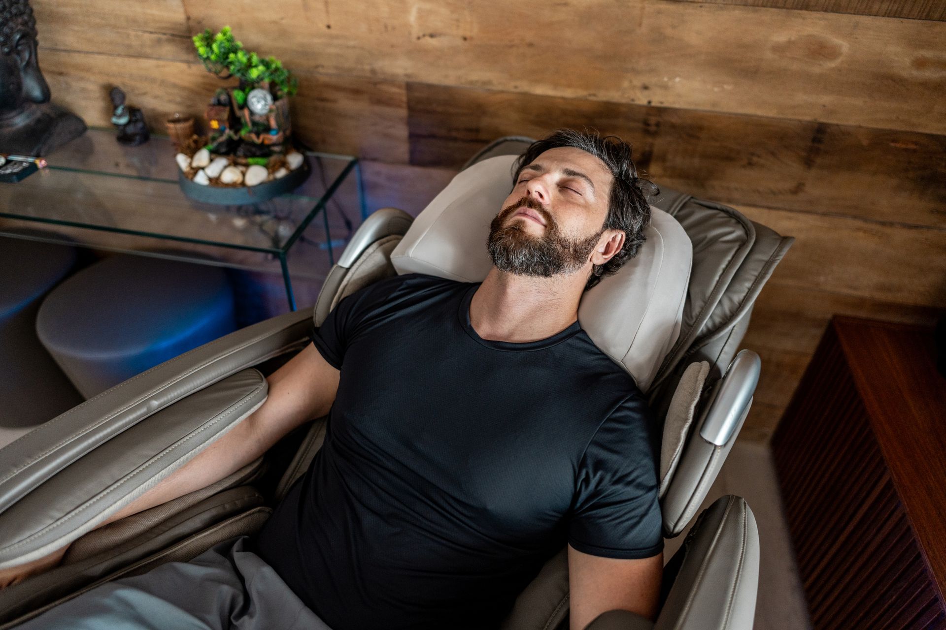 A man is laying in a massage chair with his eyes closed.