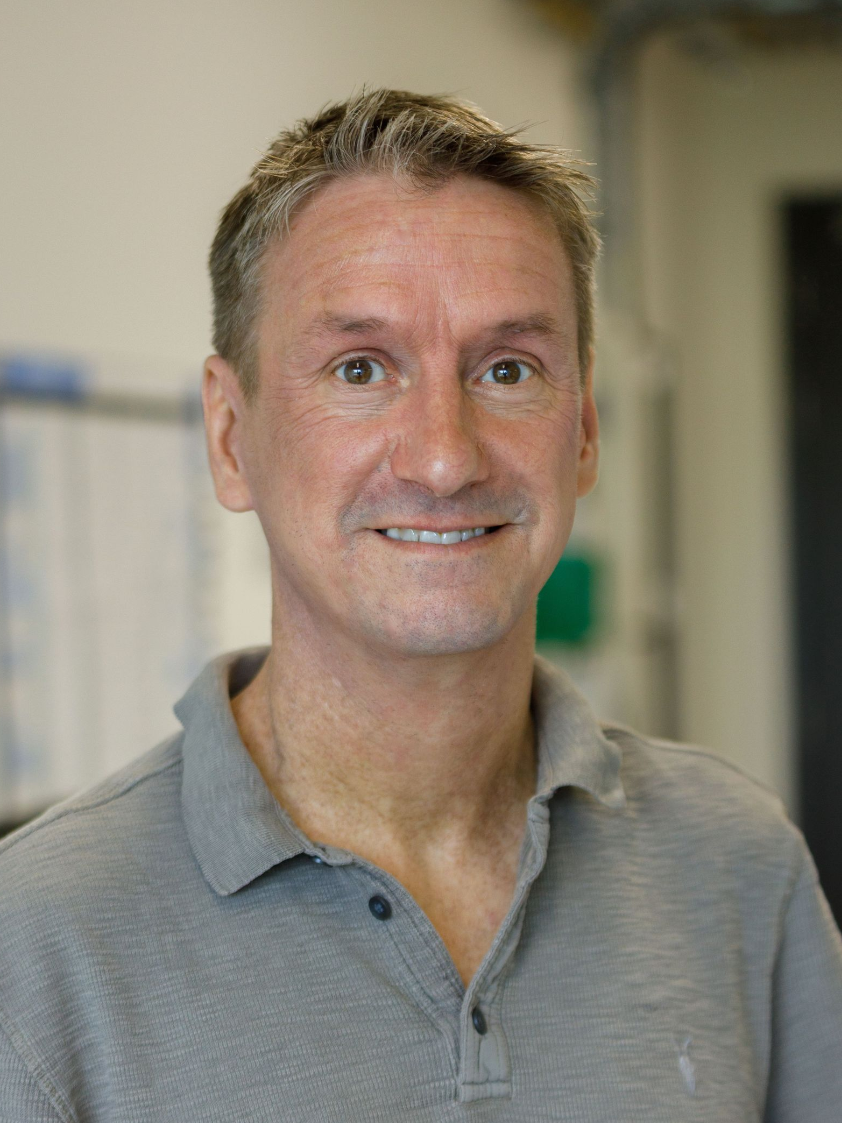 A man in a pink shirt and blue tie smiles for the camera
