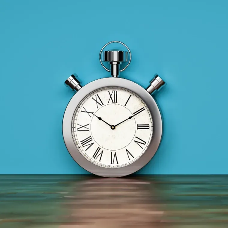 A stopwatch with roman numerals is sitting on a wooden table.