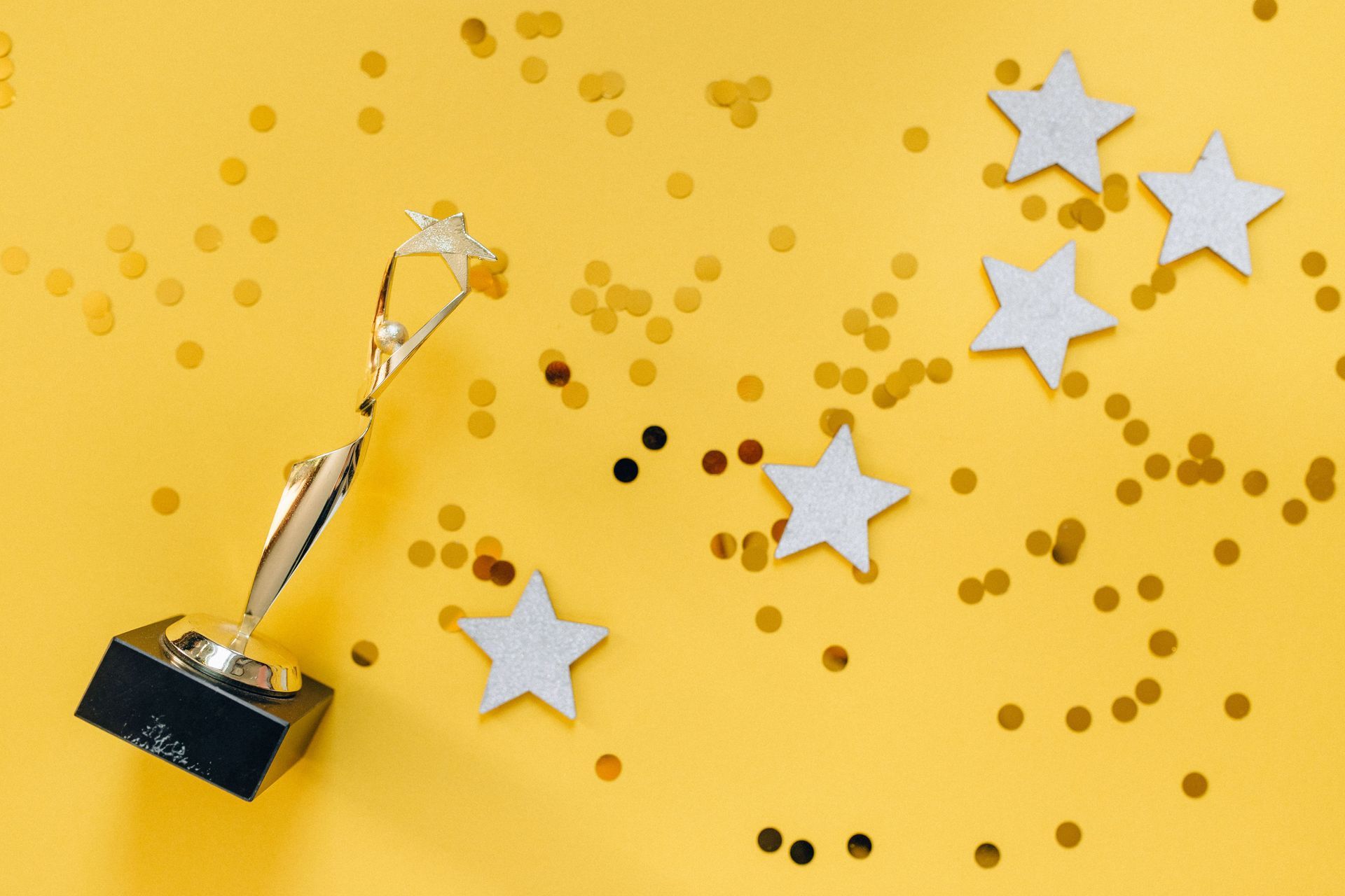 Silver trophy with star confetti on a yellow background