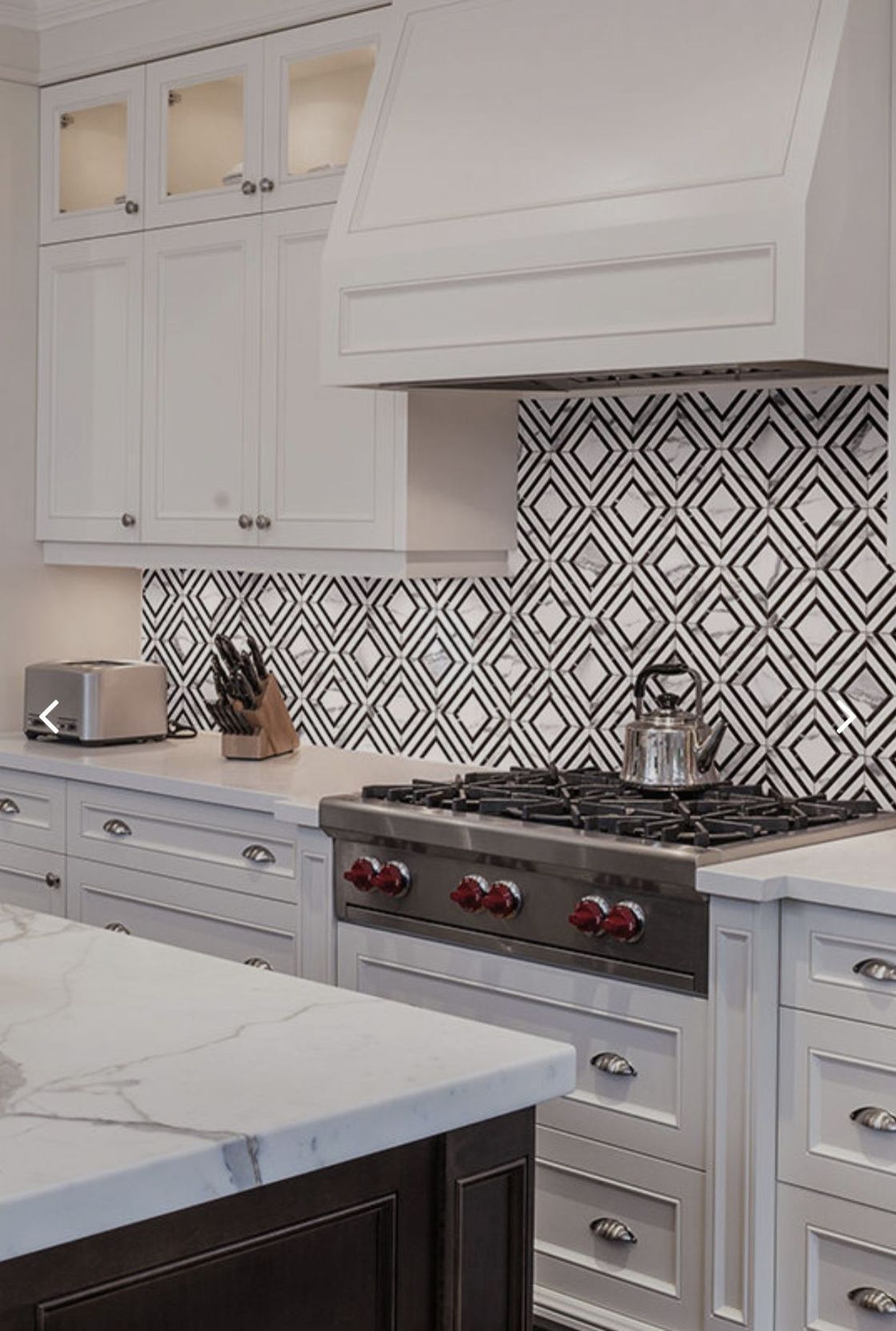 A kitchen with white cabinets , stainless steel appliances , and a stove top oven.