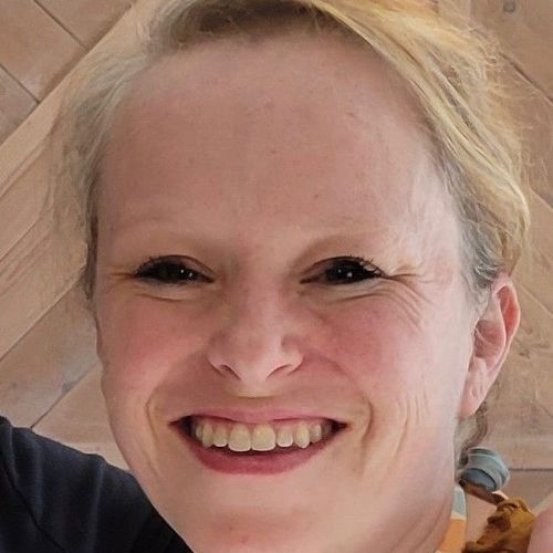 Smiling woman with blonde hair, visible teeth, looking at the camera.