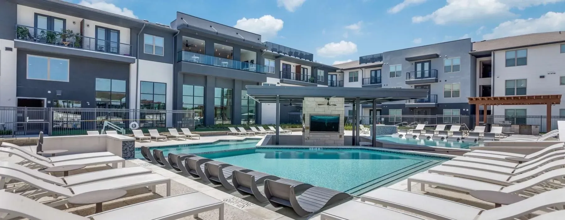 Luxury swimming pool and lounge area with modern apartment buildings in the background.