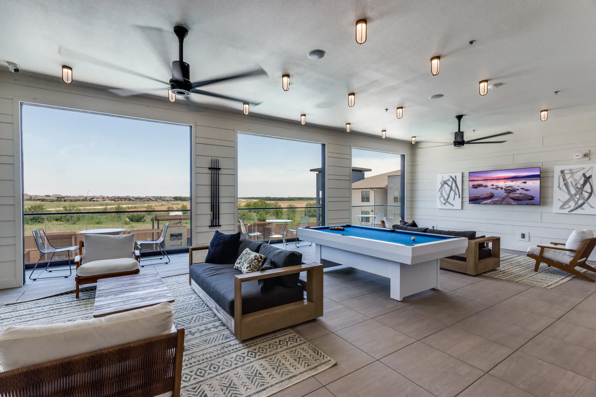 Resident lounge with pool table, seating, and large windows with a view.