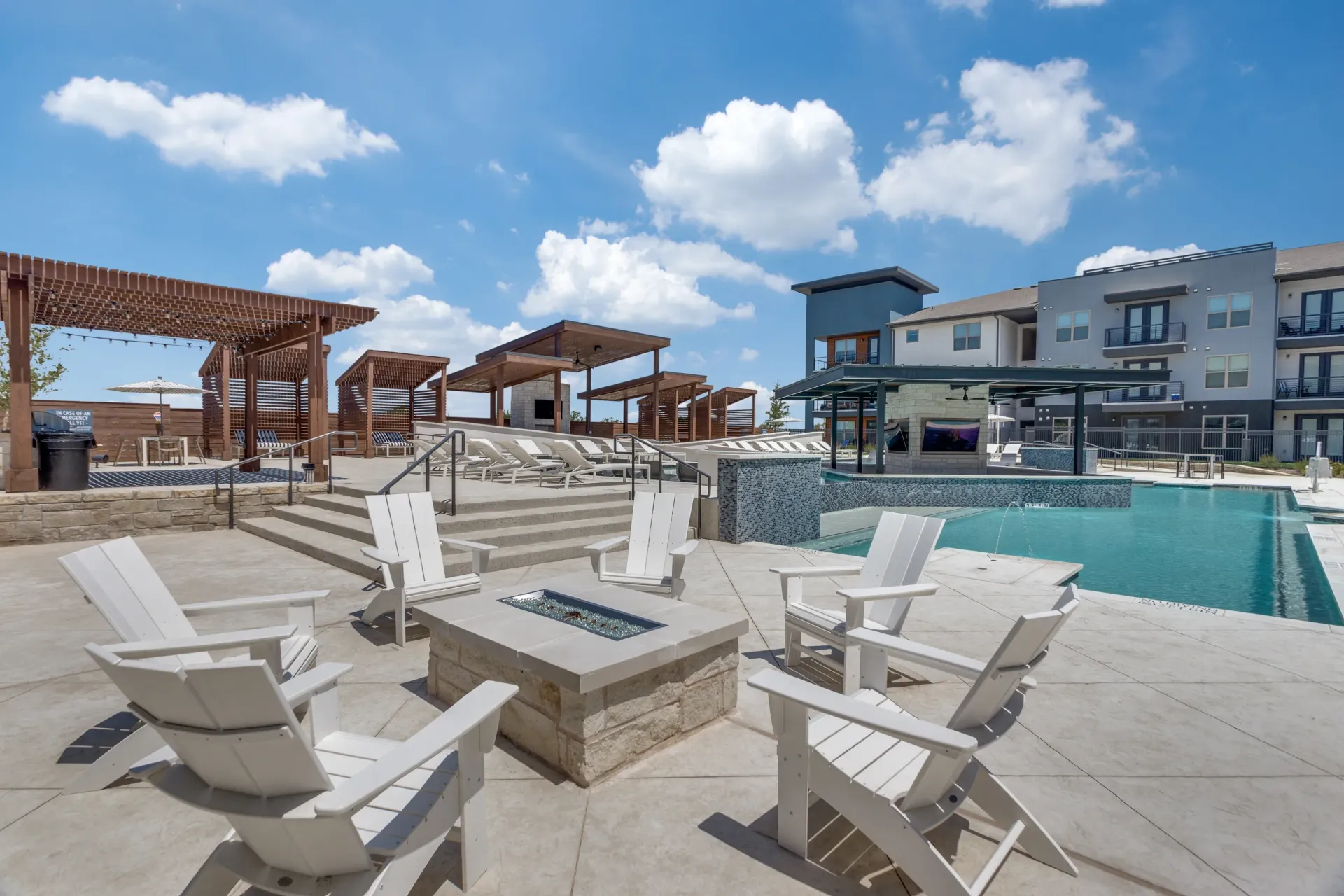 Luxury outdoor swimming pool with lounge chairs and a fire pit.
