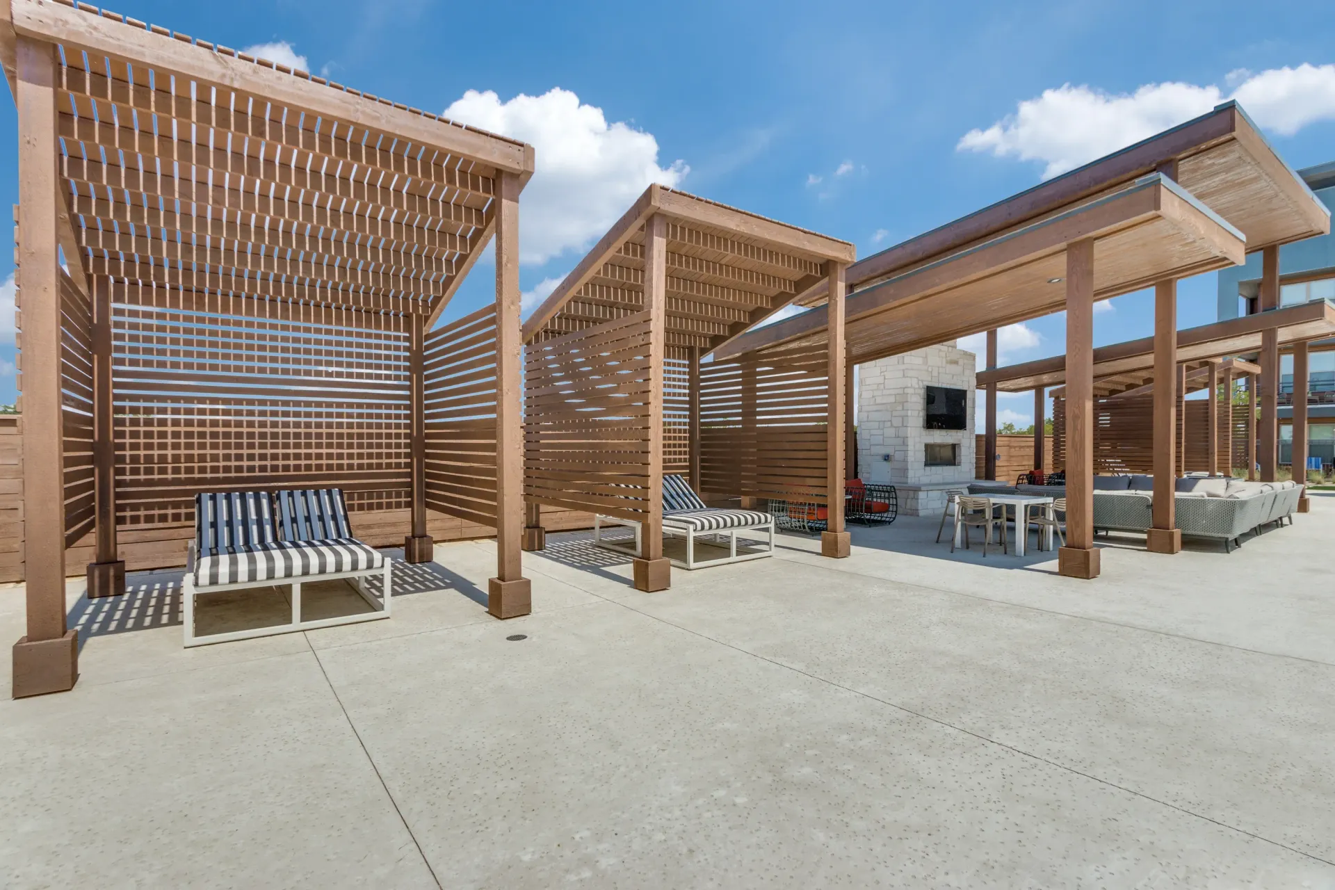 Outdoor lounge area with covered seating, fireplace, and TV.