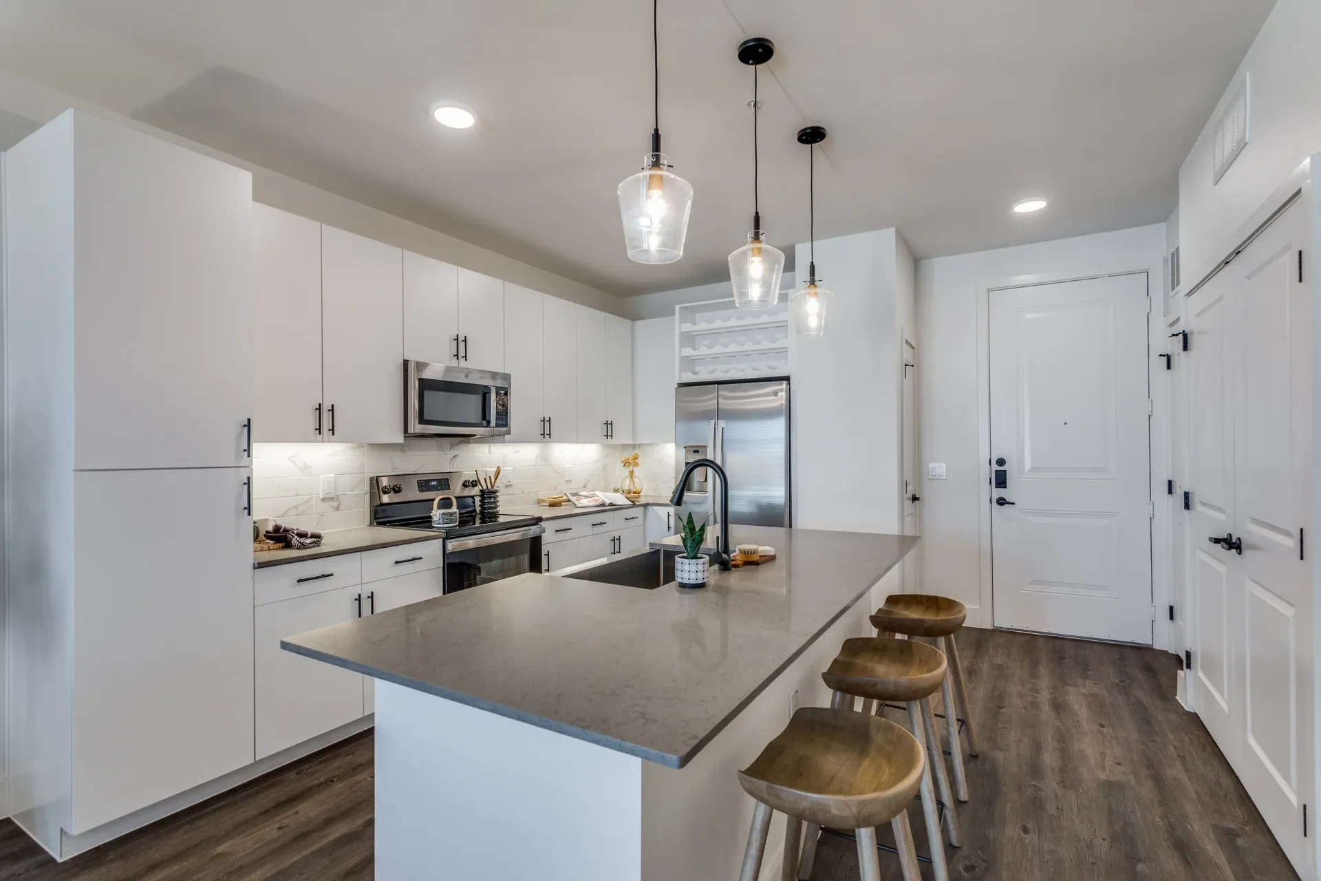 Modern kitchen with white cabinets, stainless steel appliances, and a large island with bar stools.