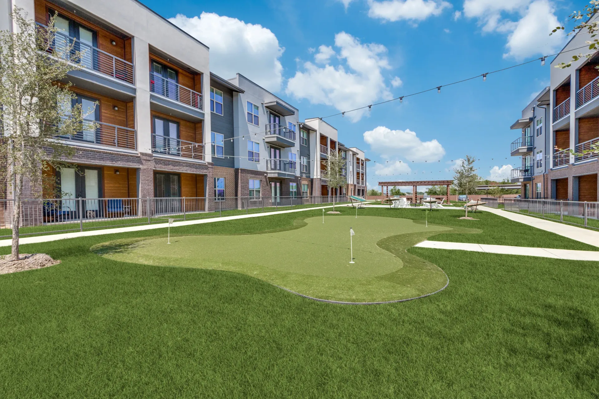 Apartment complex courtyard with putting green and seating areas.