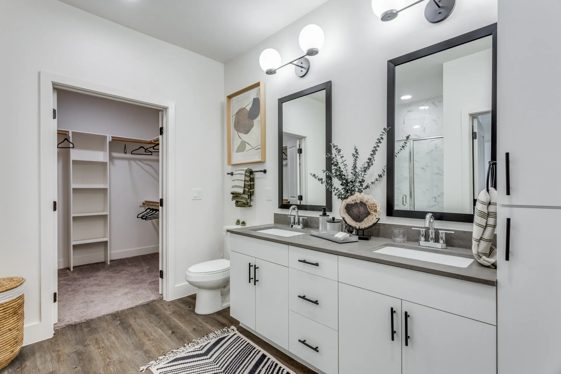 Modern bathroom with double vanity, large mirrors, and an open walk-in closet.