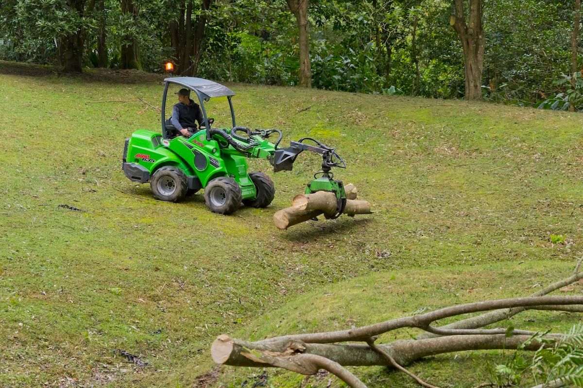 A Bulldozer Is Driving Down a Dirt Road in The Woods — Burnett Trees in Kiama, NSW