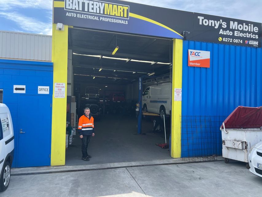Car repair shop entrance with a worker in an orange vest standing in the doorway
