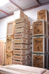 Wooden crates stacked in a warehouse. Some crates are labeled and feature different sizes and textures.