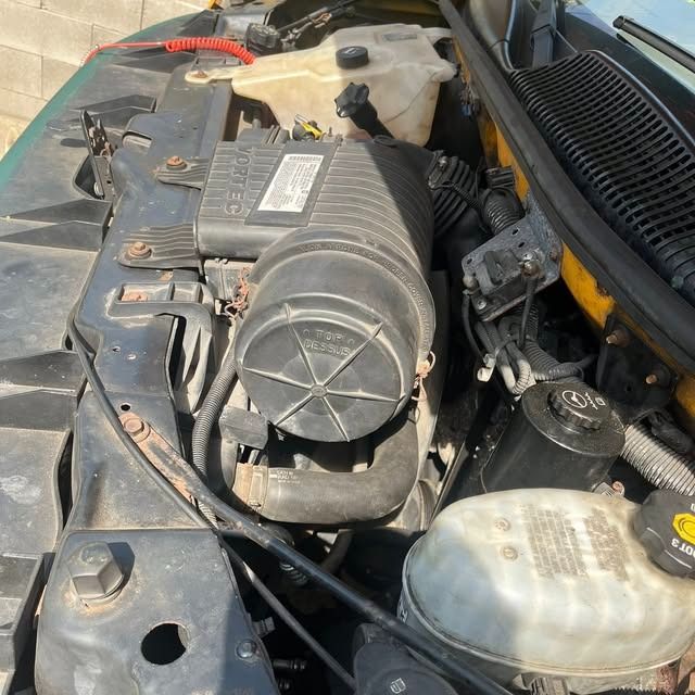 Open car engine bay with air intake, coolant reservoir, and visible hoses and wiring