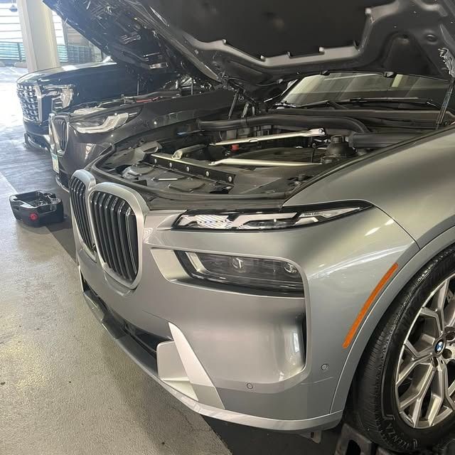 Silver BMW SUV with open hood in a garage, front view, engine exposed