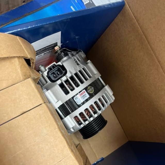 Alternator in a cardboard box, wrapped in blue packaging material.