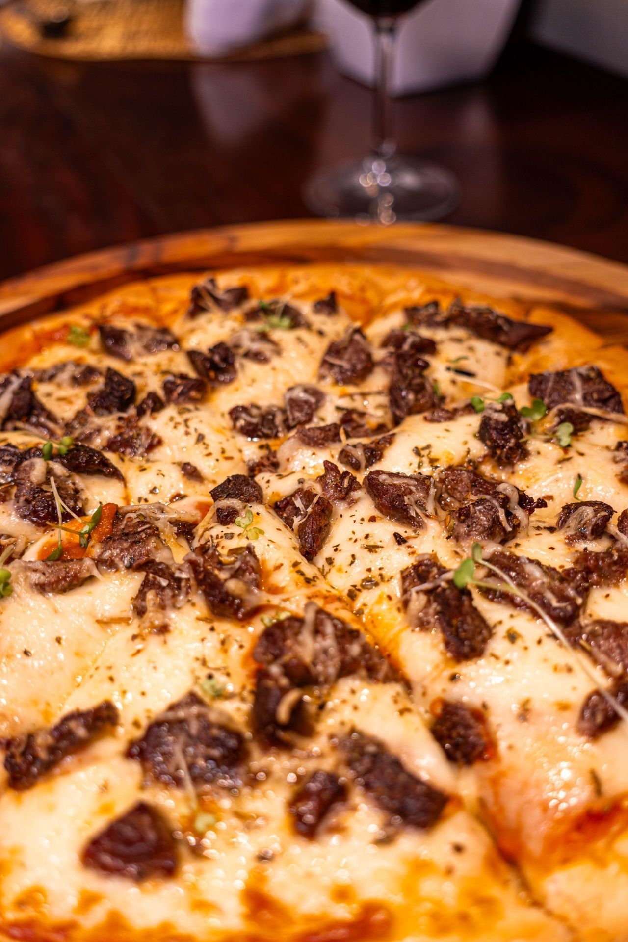 Close-up de uma pizza de queijo e cogumelos sobre uma mesa de madeira